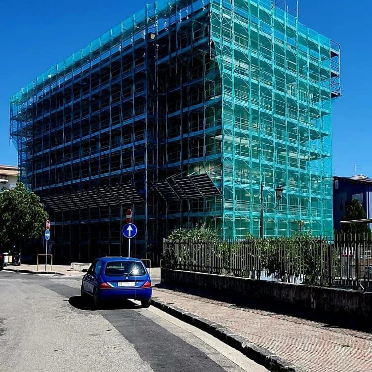 Un'auto blu è parcheggiata davanti a un edificio in costruzione