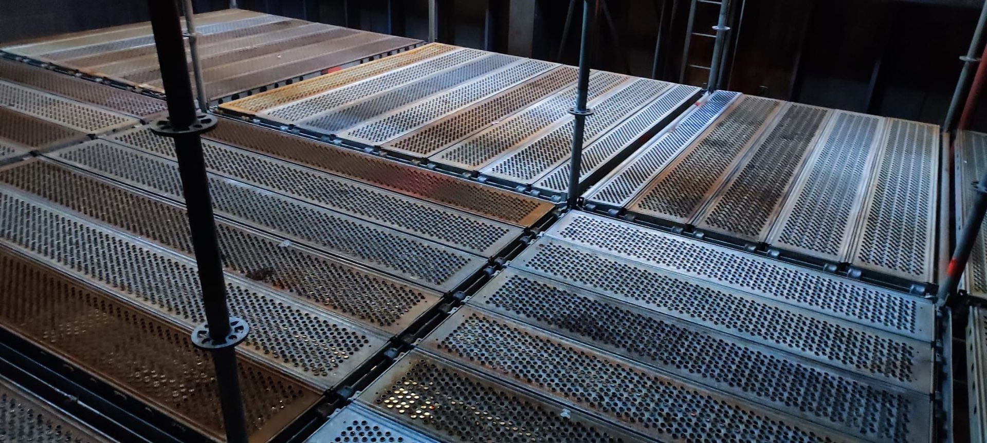 Una fila di impalcature metalliche appoggiate su un pavimento in legno.