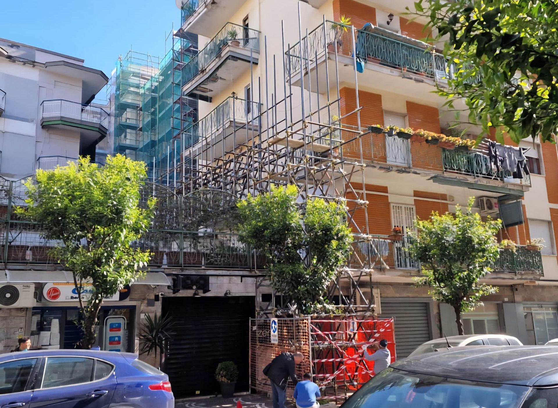 Un'auto blu è parcheggiata davanti a un edificio con sopra delle impalcature