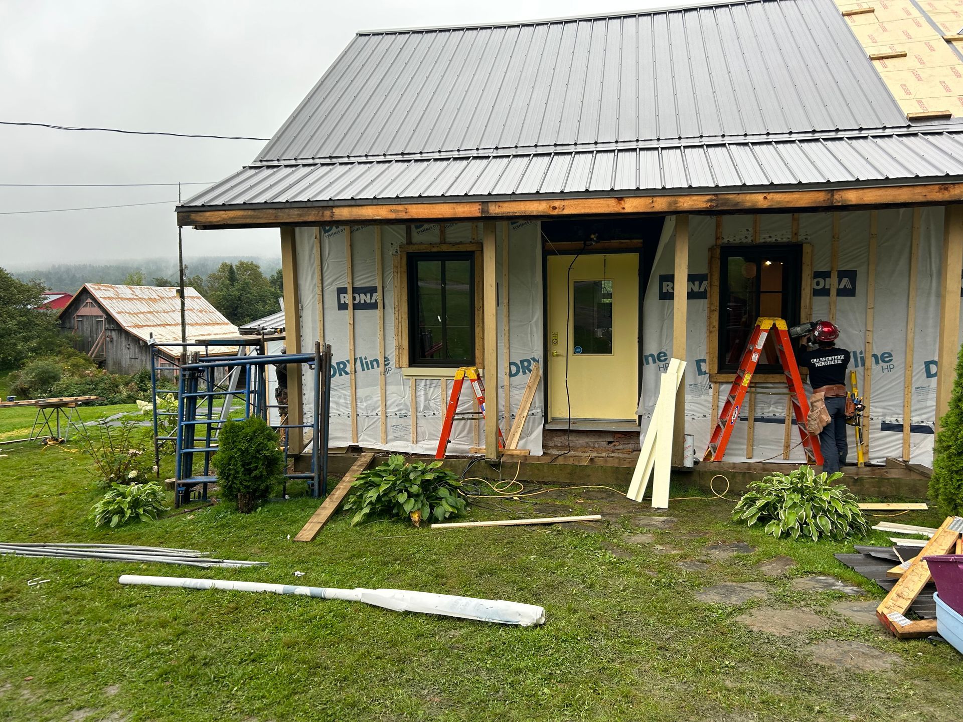 Une maison est en construction avec un toit en métal et un porche.