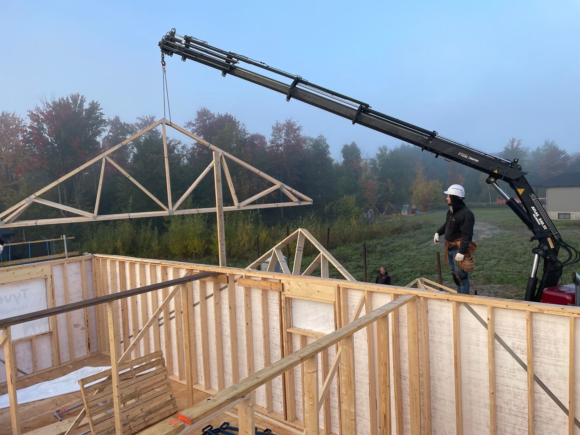 Un homme utilise une grue pour soulever une structure en bois