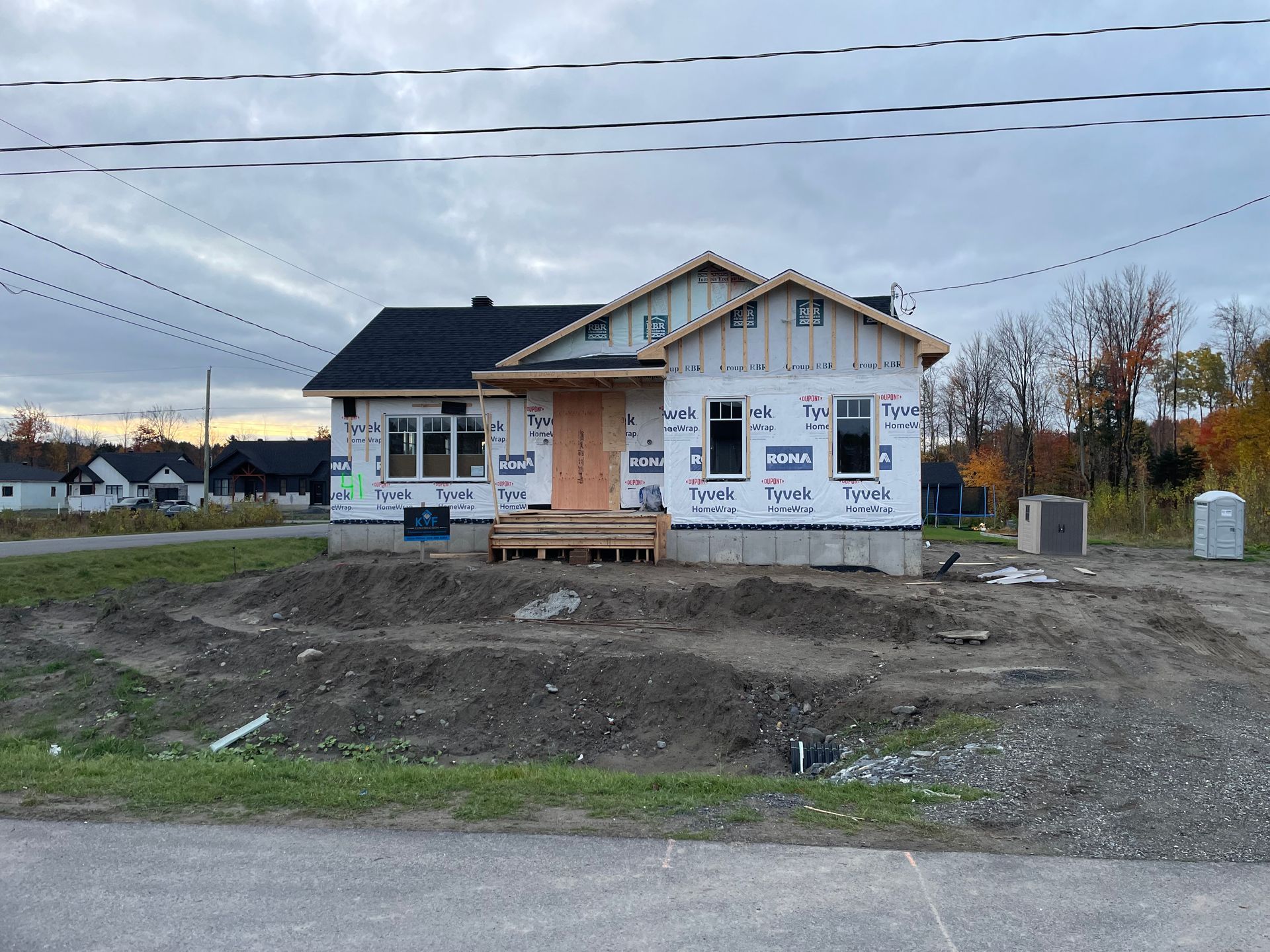 Une maison est en construction au milieu d'un champ de terre.