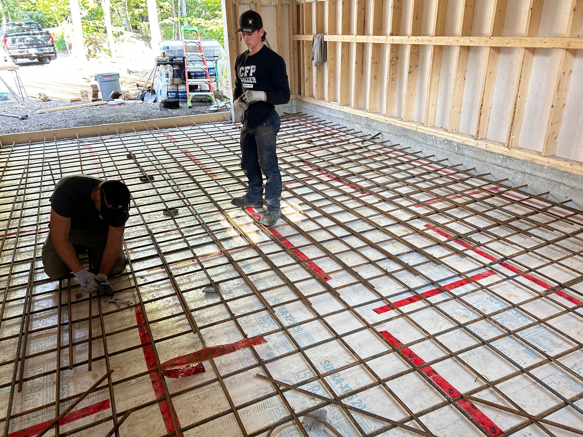 Deux hommes travaillent sur un sol en béton dans un garage.