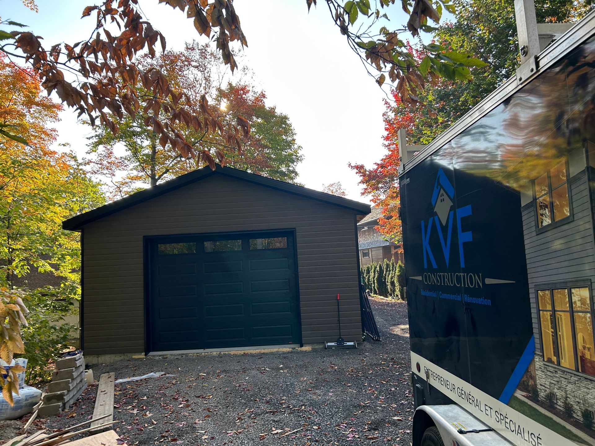 Un garage avec une porte de garage noire et une remorque devant.