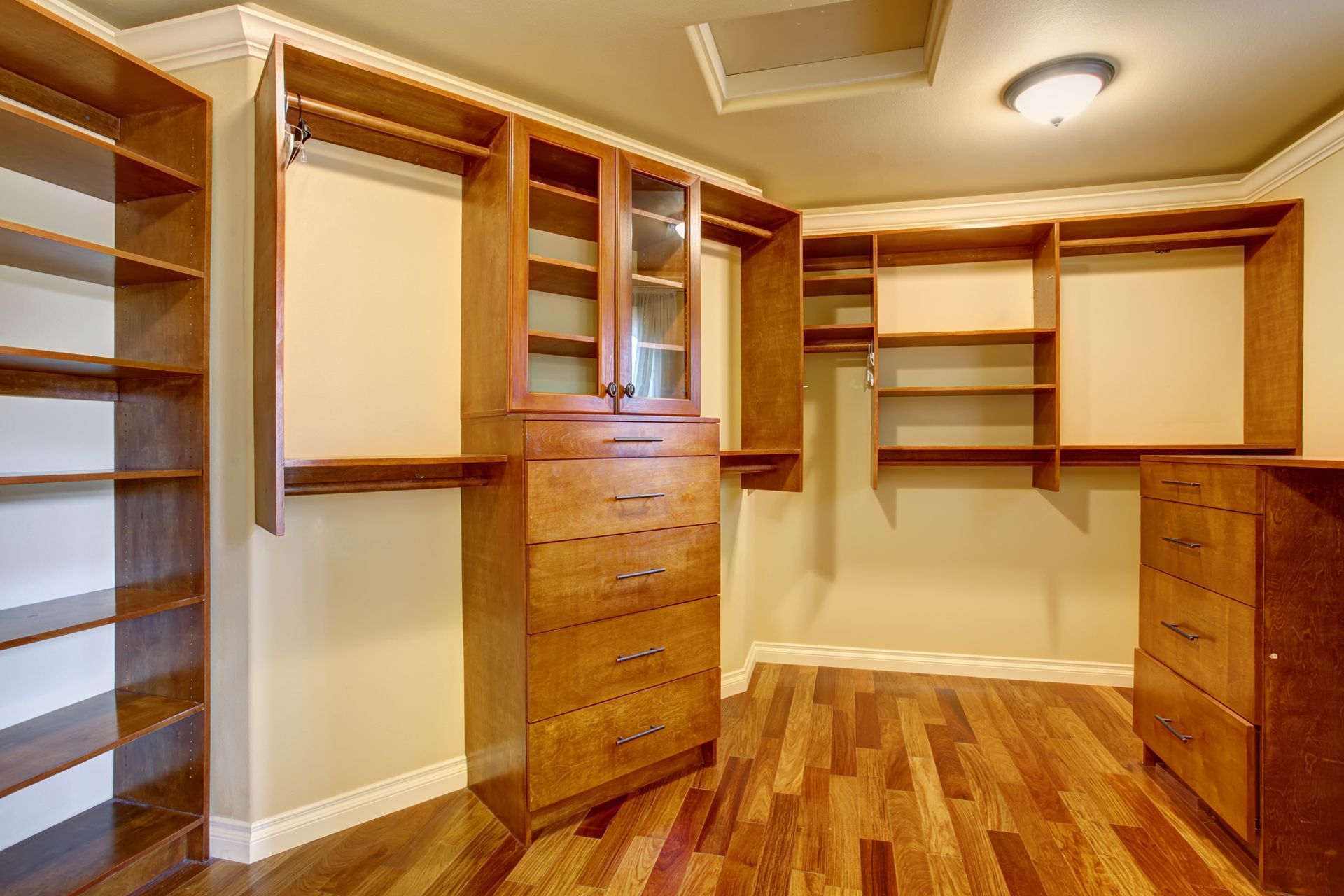 A walk-in closet with hardwood floors and lots of shelves and drawers