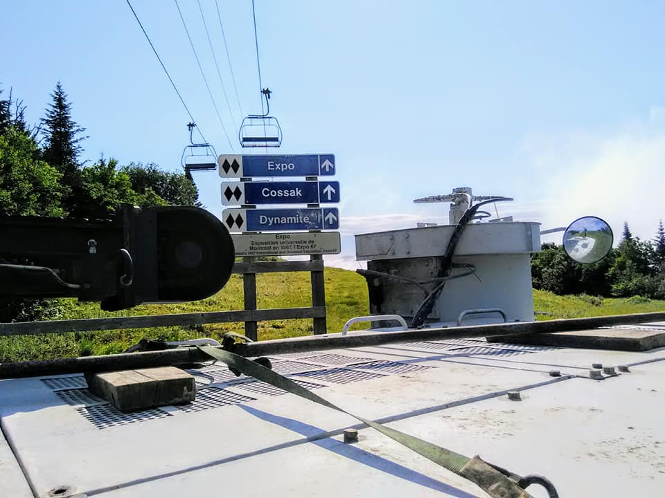 Panneaux indiquant aux skieurs les différentes pistes d'une station de ski, avec un télésiège en arrière-plan.
