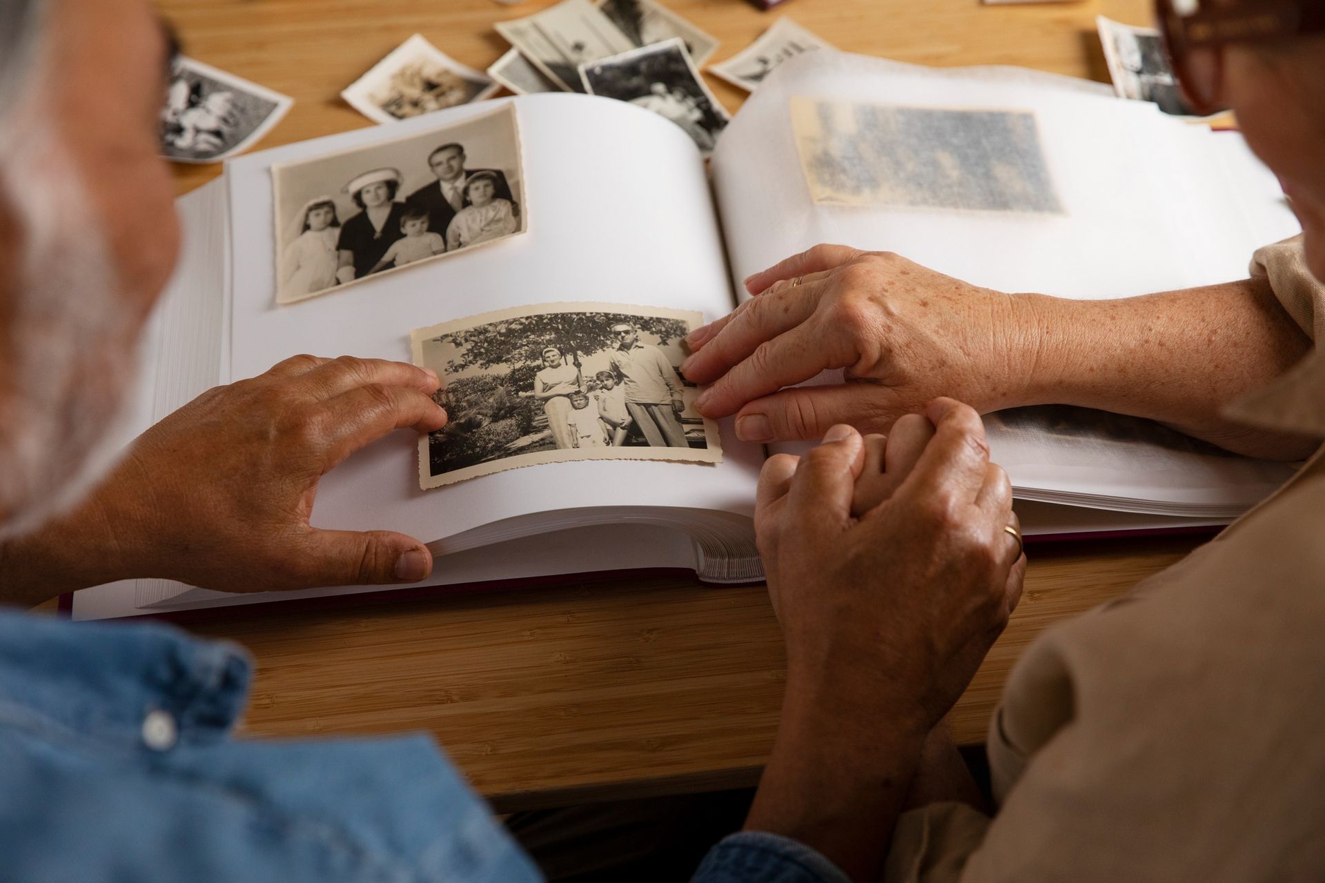 Elderly couple looking at a photo album, indoors, with sepia-toned photos.