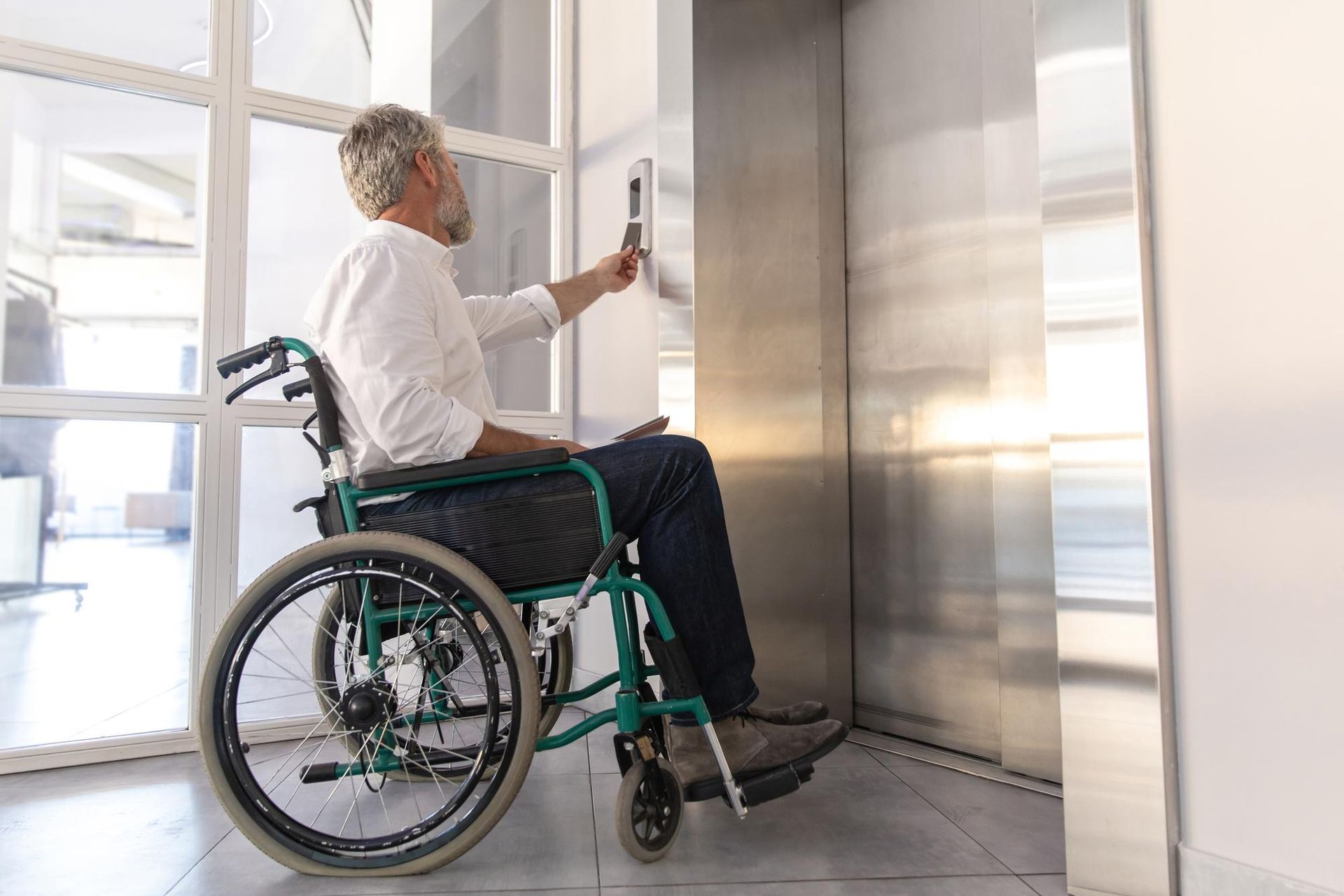 Man in wheelchair presses elevator button.
