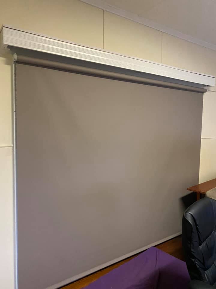 A Large Gray Blind is Hanging on a Wall in a Living Room — Mareeba Floor Coverings Centre in Tablelands, QLD