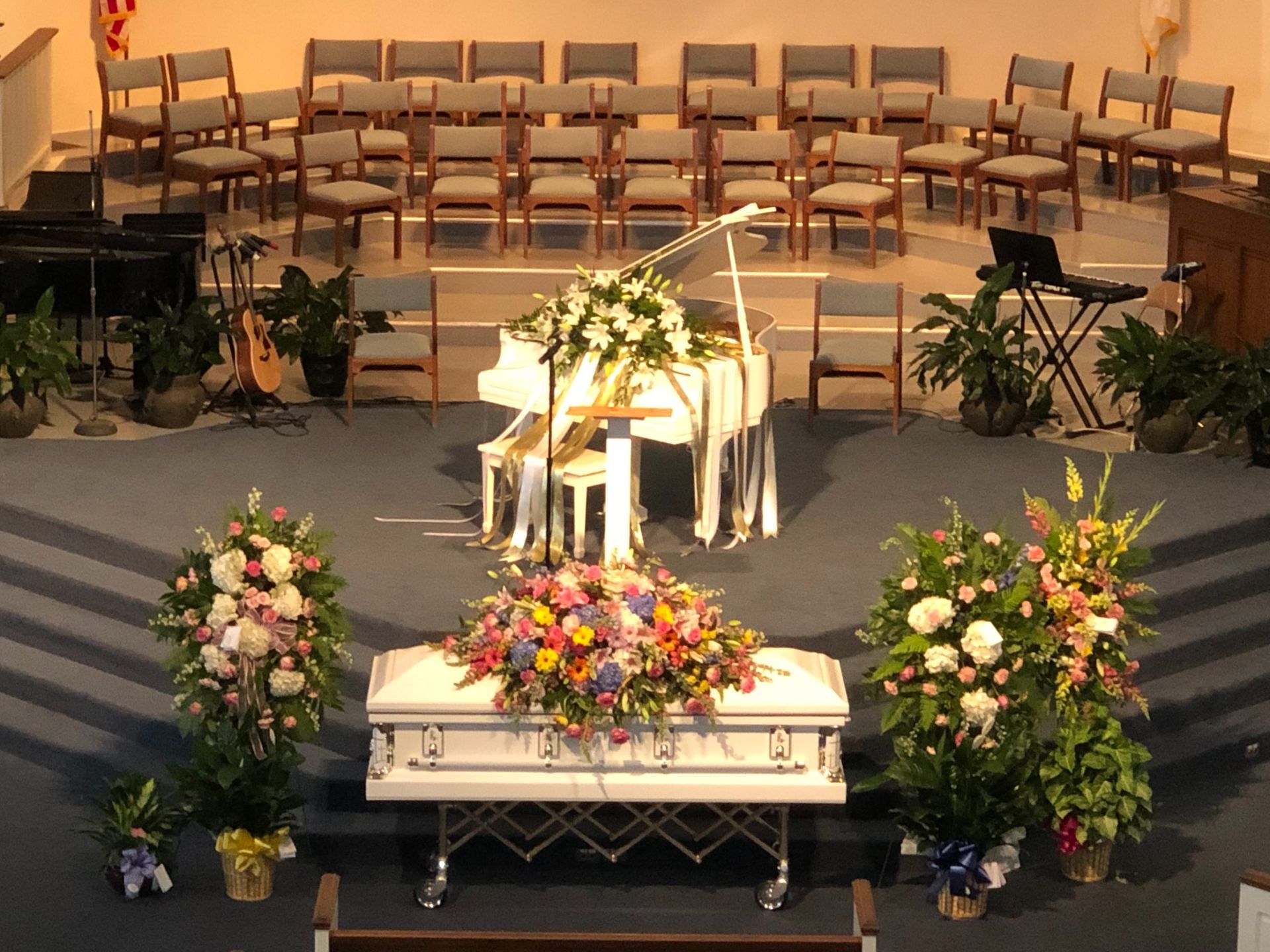 A man in a suit is sitting at a coffin at a funeral.