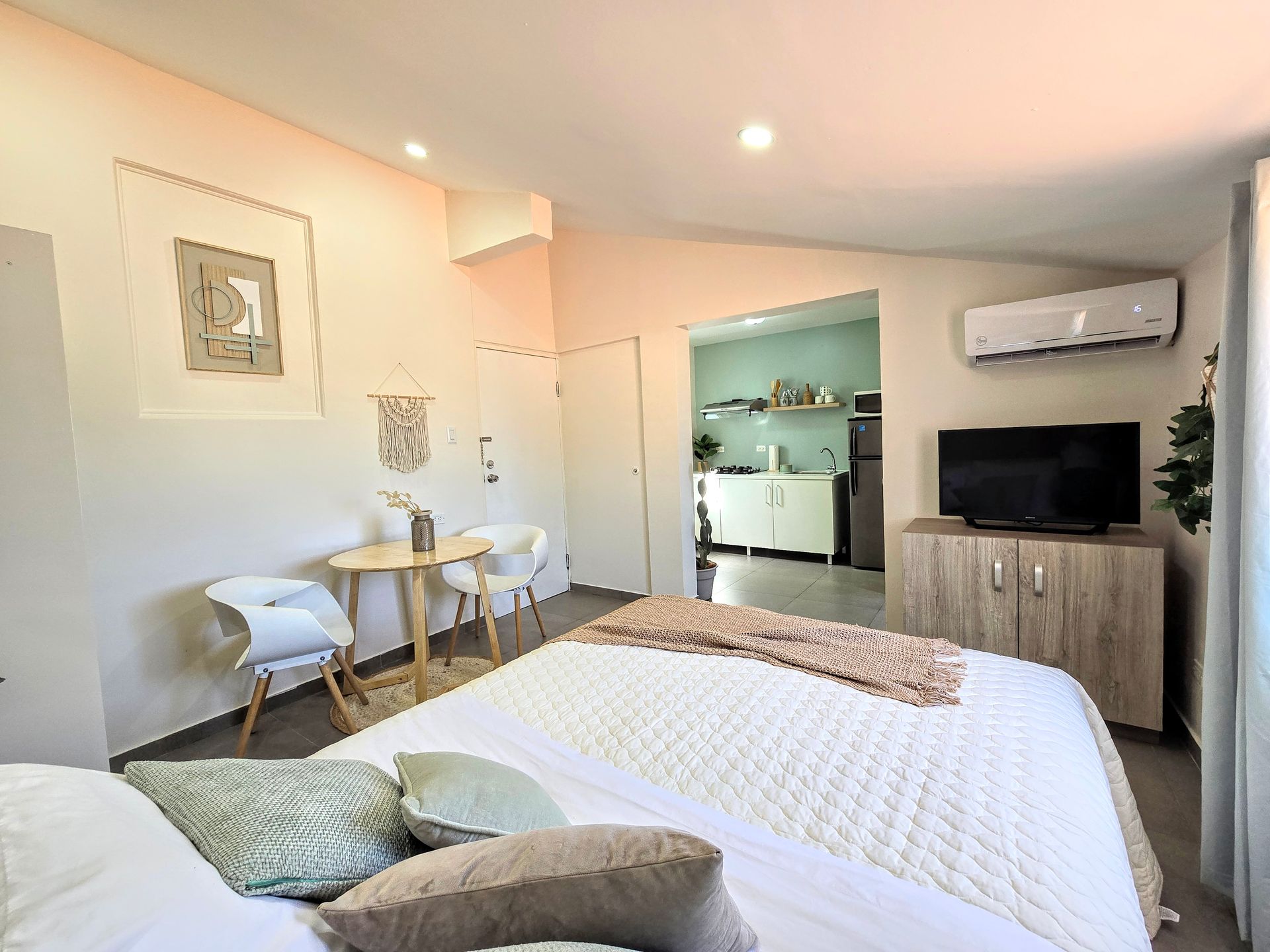 A bedroom with a bed , television , table and chairs.