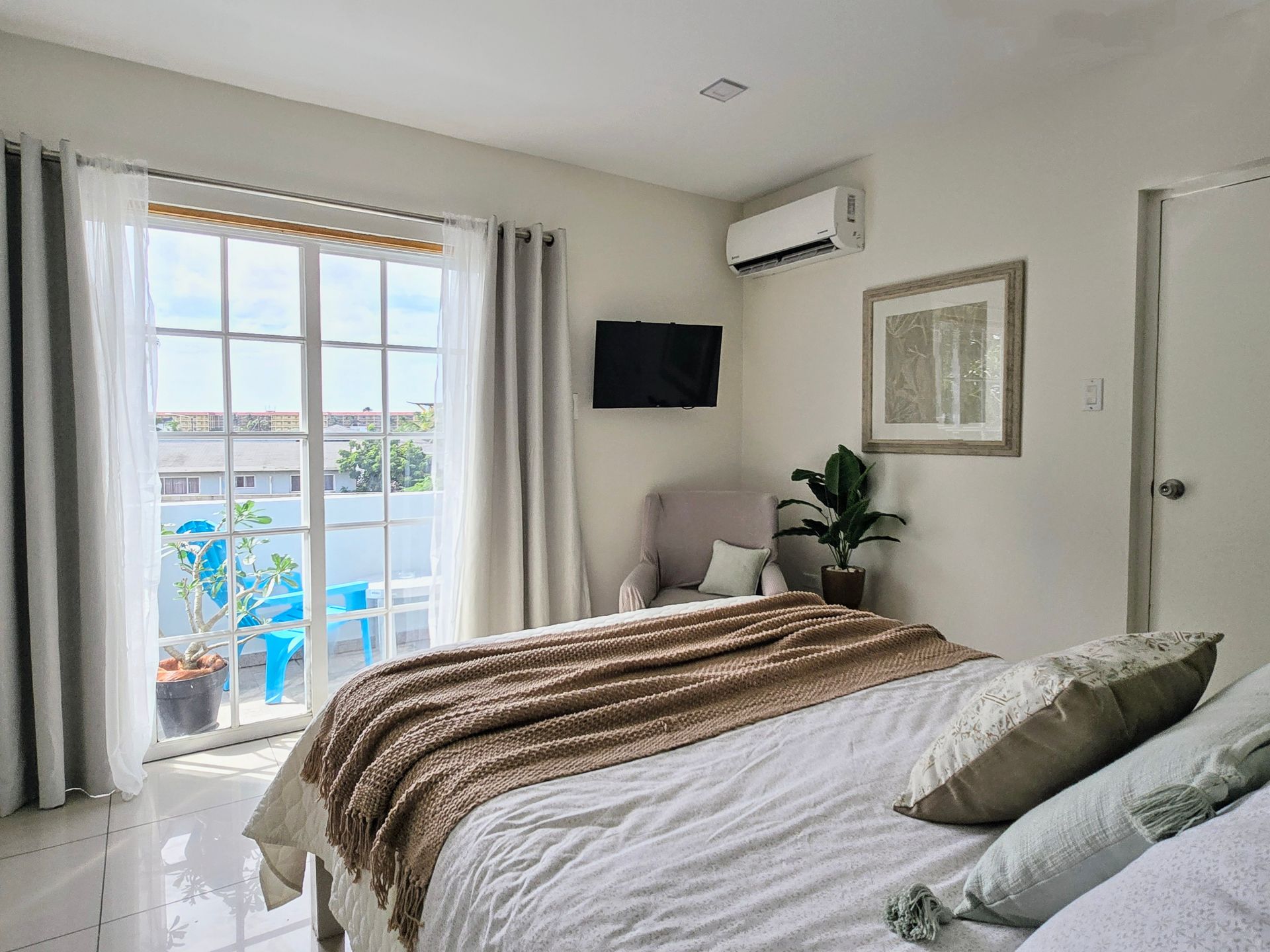 A bedroom with a bed , chair , television and sliding glass doors.