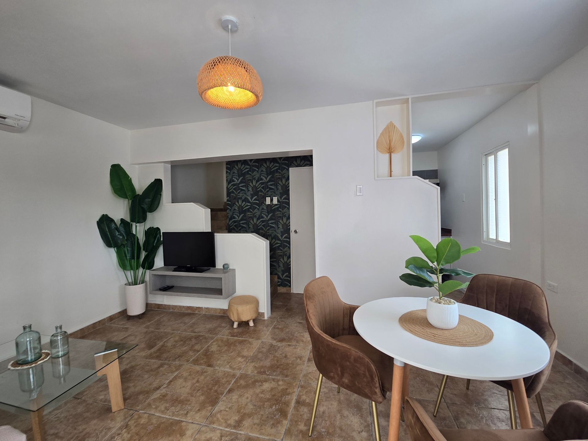 A living room with a dining table , chairs , a flat screen tv and a ceiling fan.