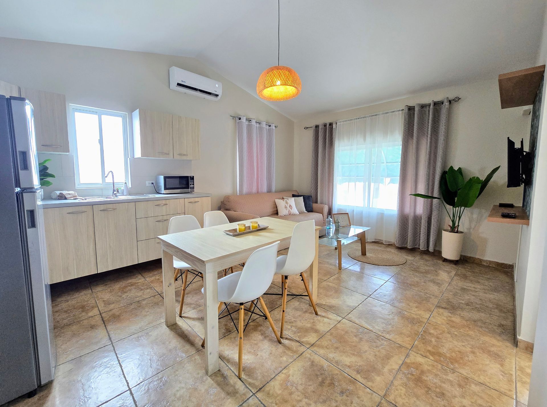 A living room with a dining table , chairs , a flat screen tv and a ceiling fan.