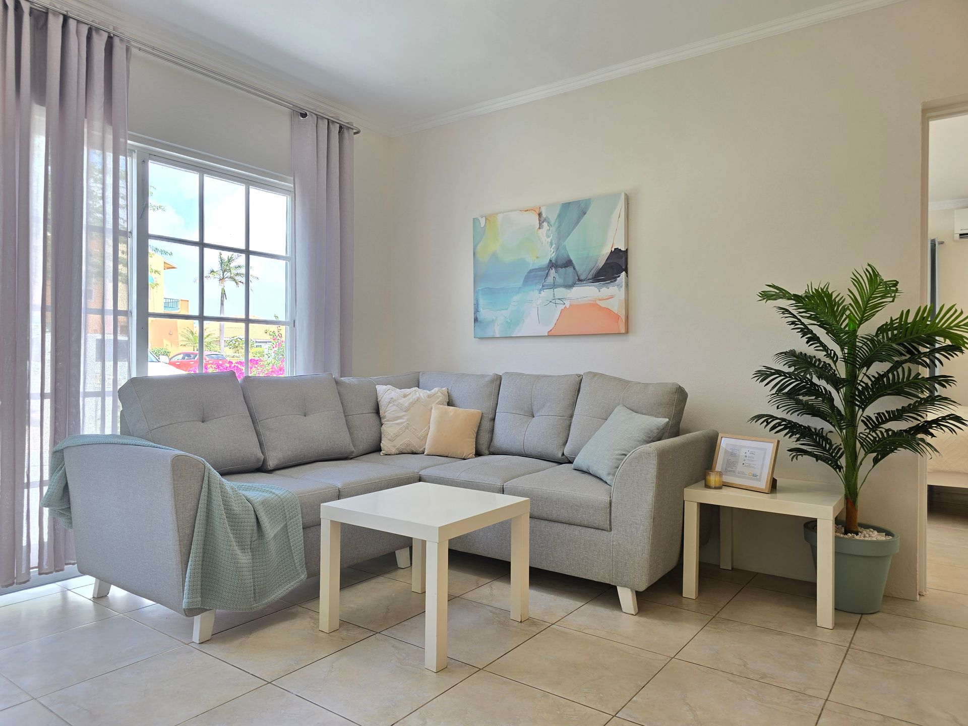 A living room with a couch , chairs , tables and a painting on the wall.