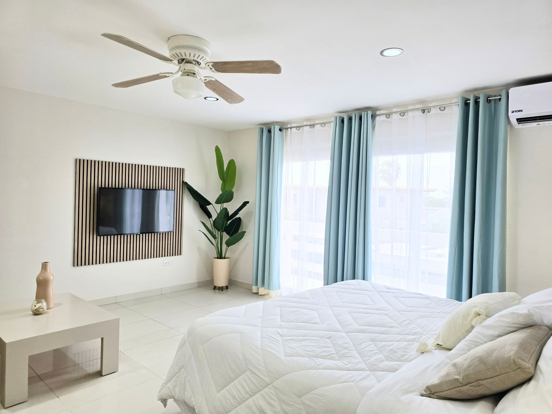 A bedroom with a bed , couch , television and ceiling fan.