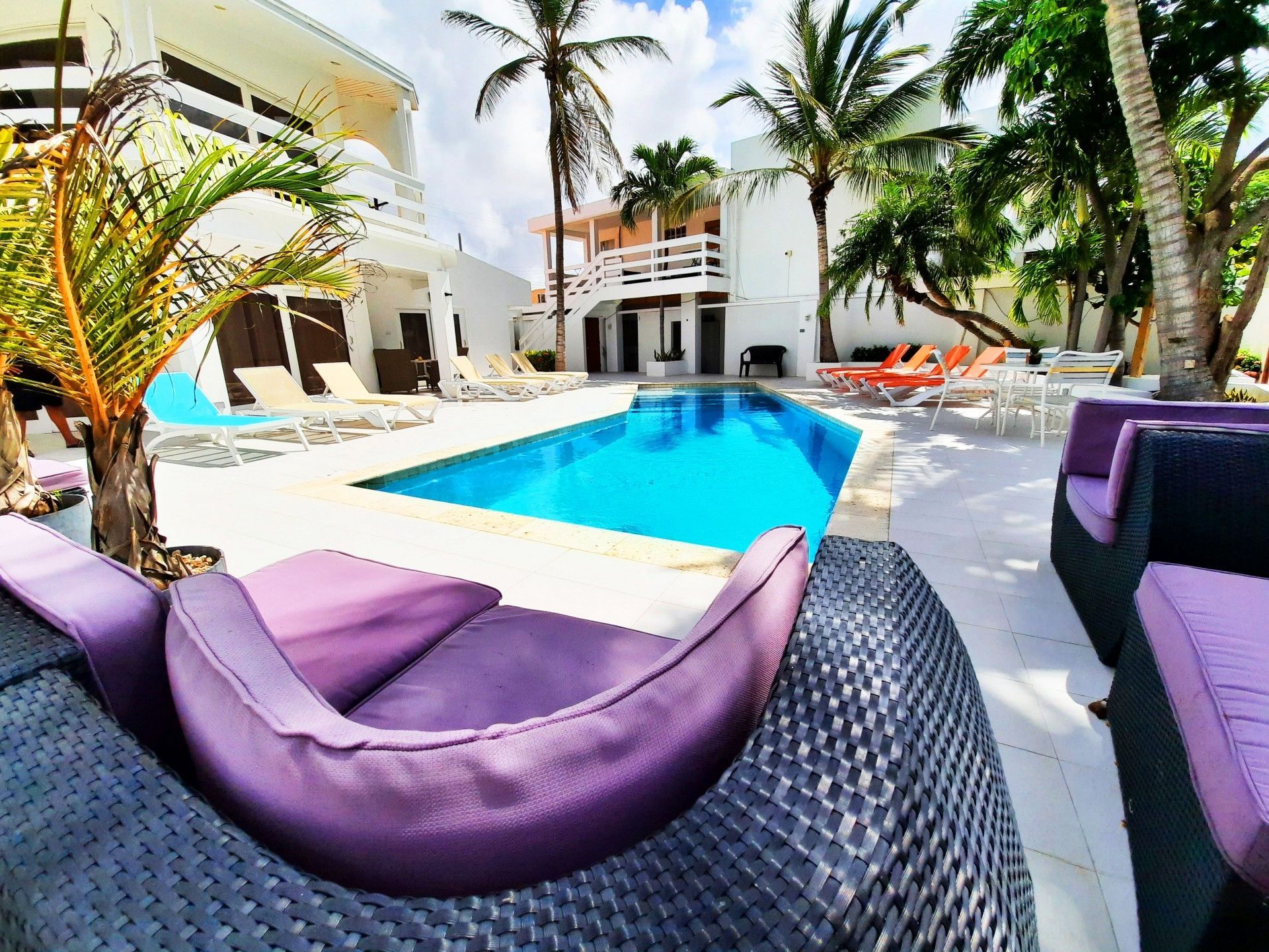 Una gran piscina rodeada de sillas y palmeras.