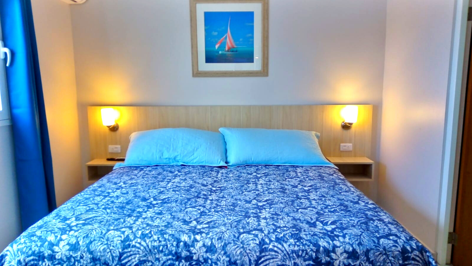 There is a picture of a sailboat on the wall above the bed.