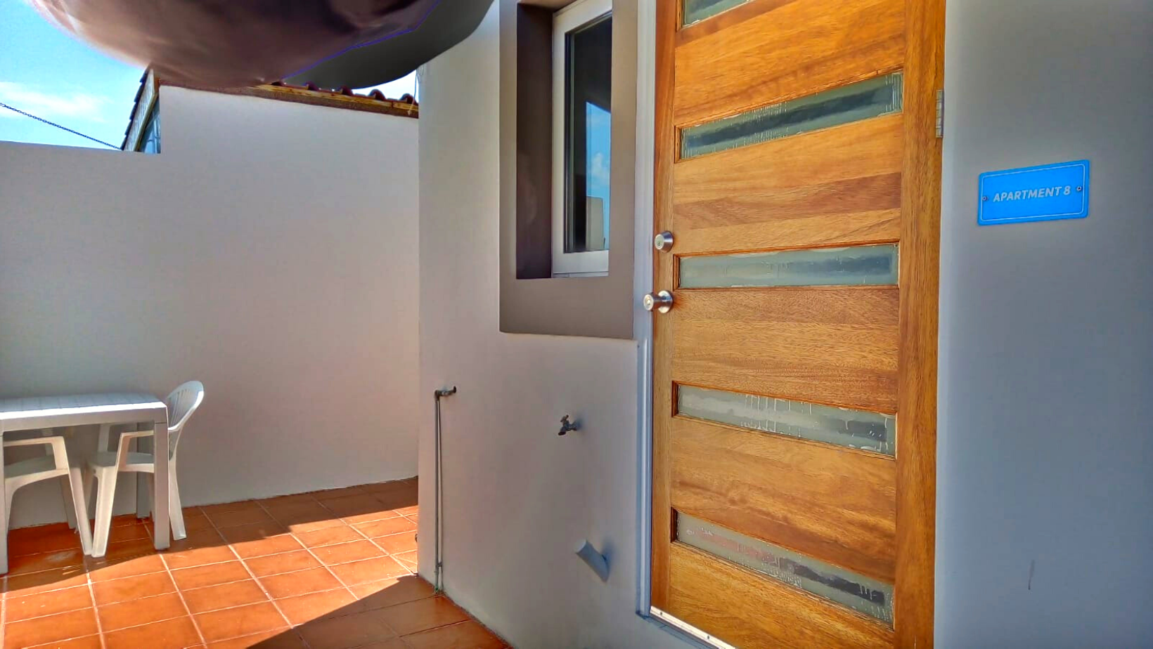 A wooden door is open to a patio with a table and chairs.