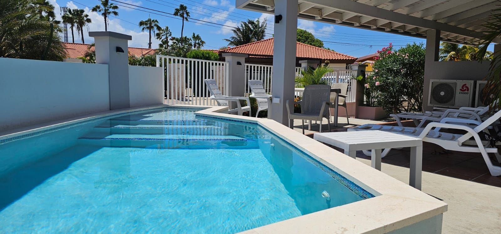 A large swimming pool surrounded by chairs and palm trees