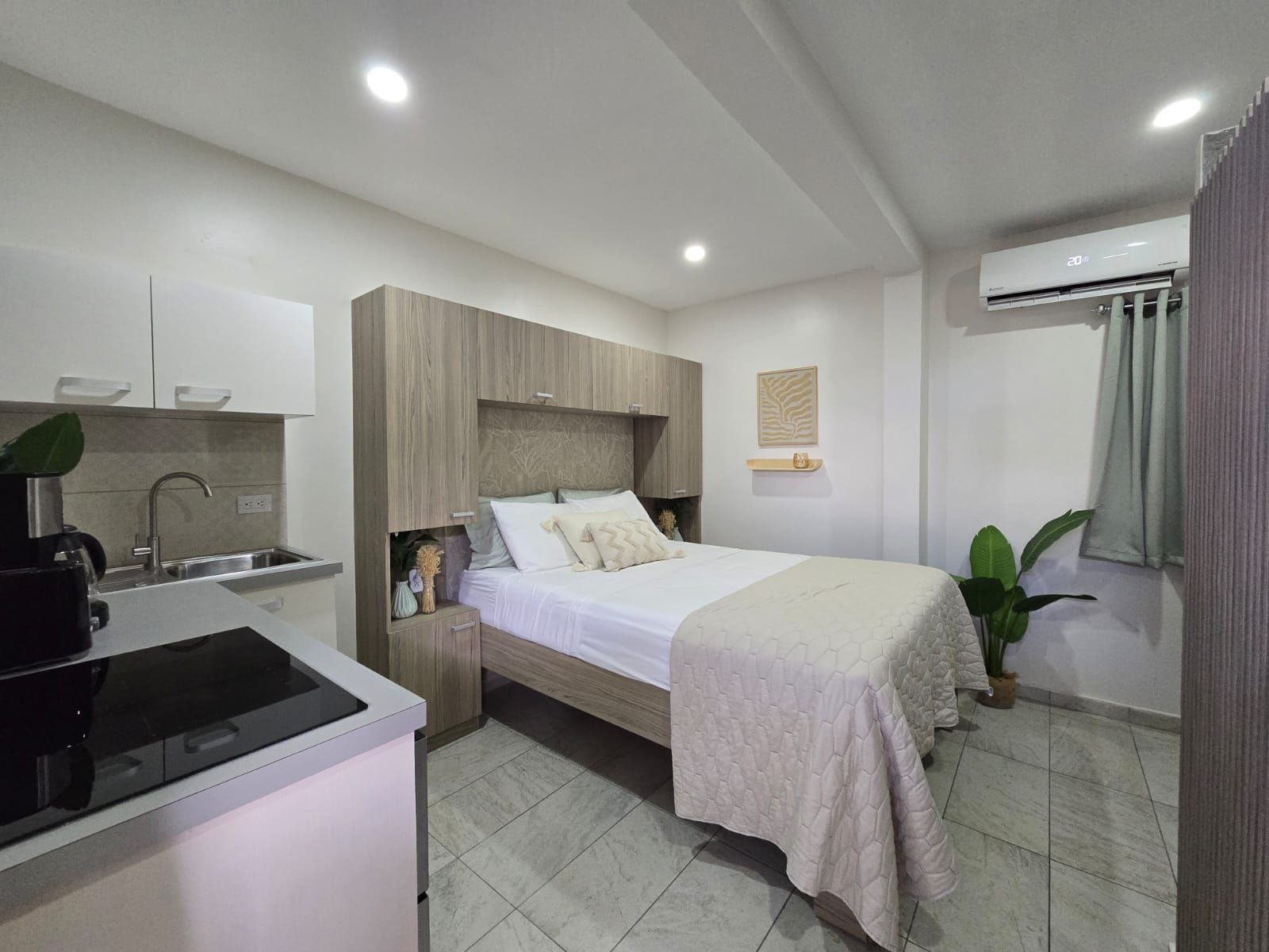 A bedroom with a bed and a kitchen in it.