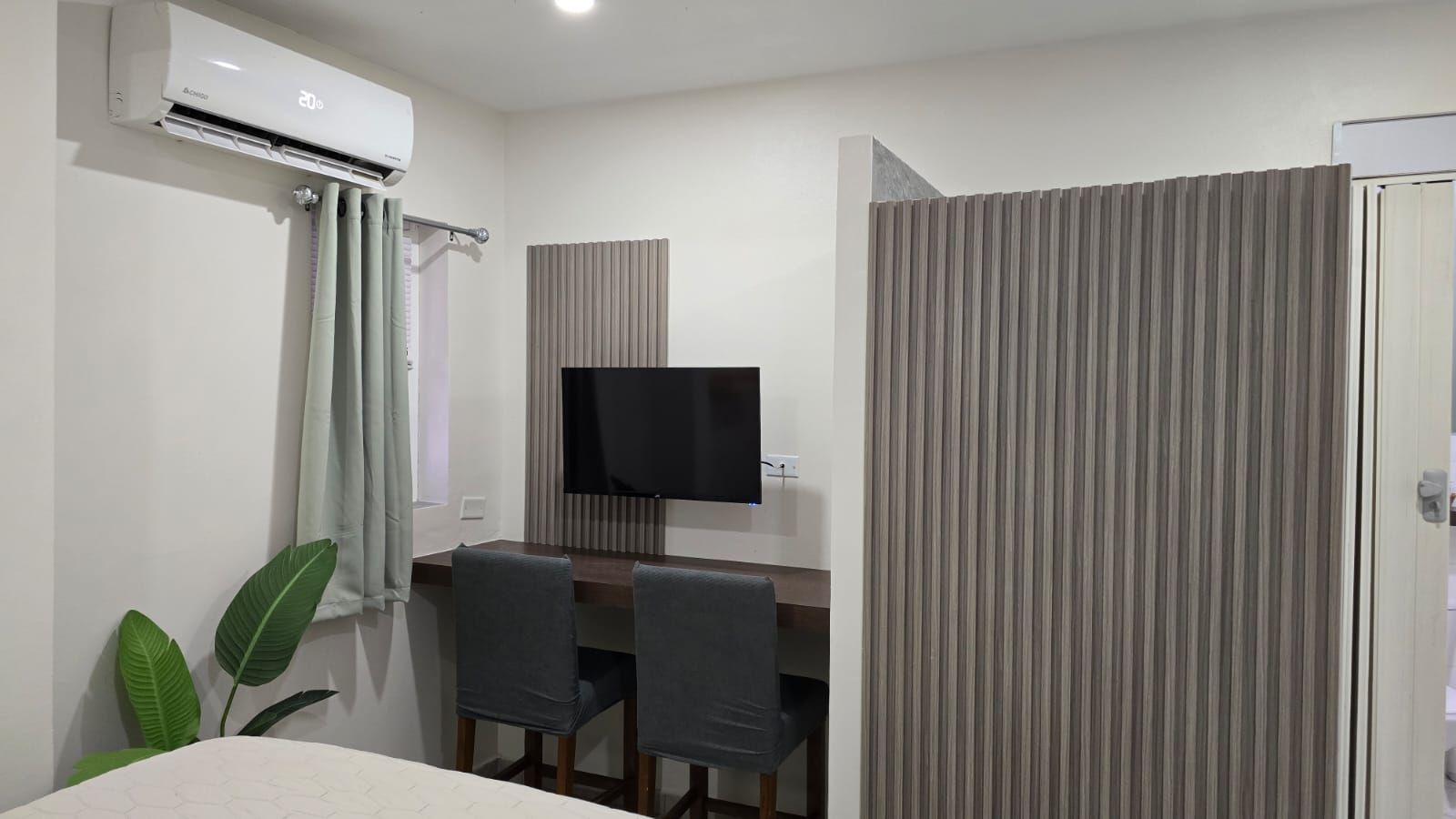 A bedroom with a bed , desk , chairs and a television.