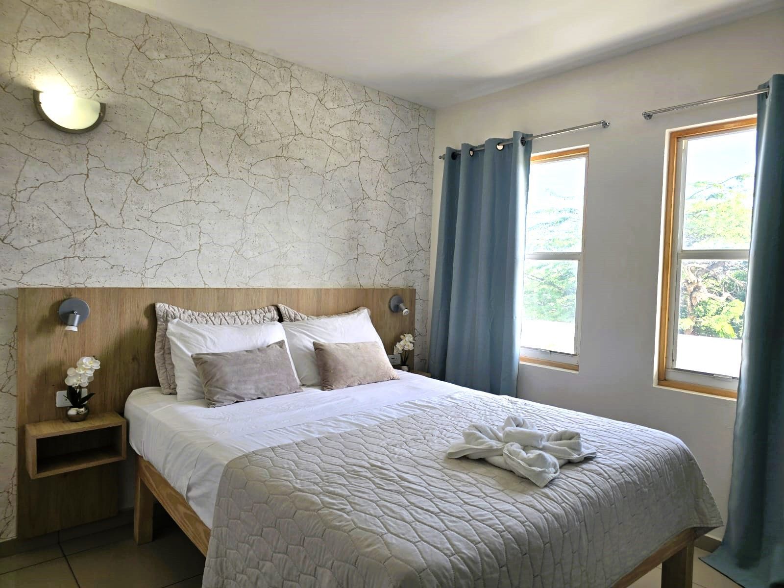 A bedroom with a bed , television and two windows.