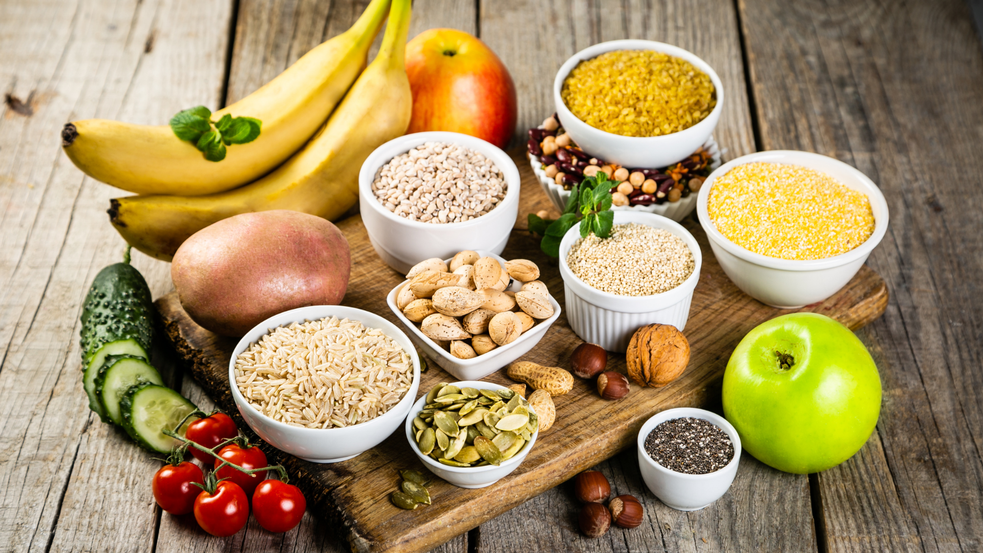 Assortment of fruits, vegetables, grains, and nuts on a wooden surface.