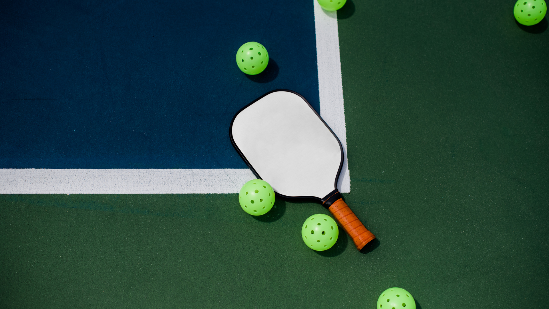A paddle and balls are on a tennis court.