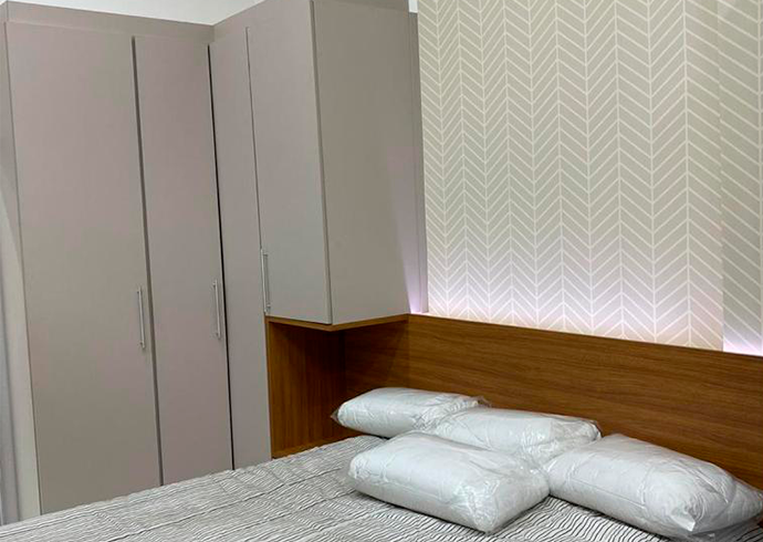 Um quarto com cama, travesseiros e guarda-roupa.
