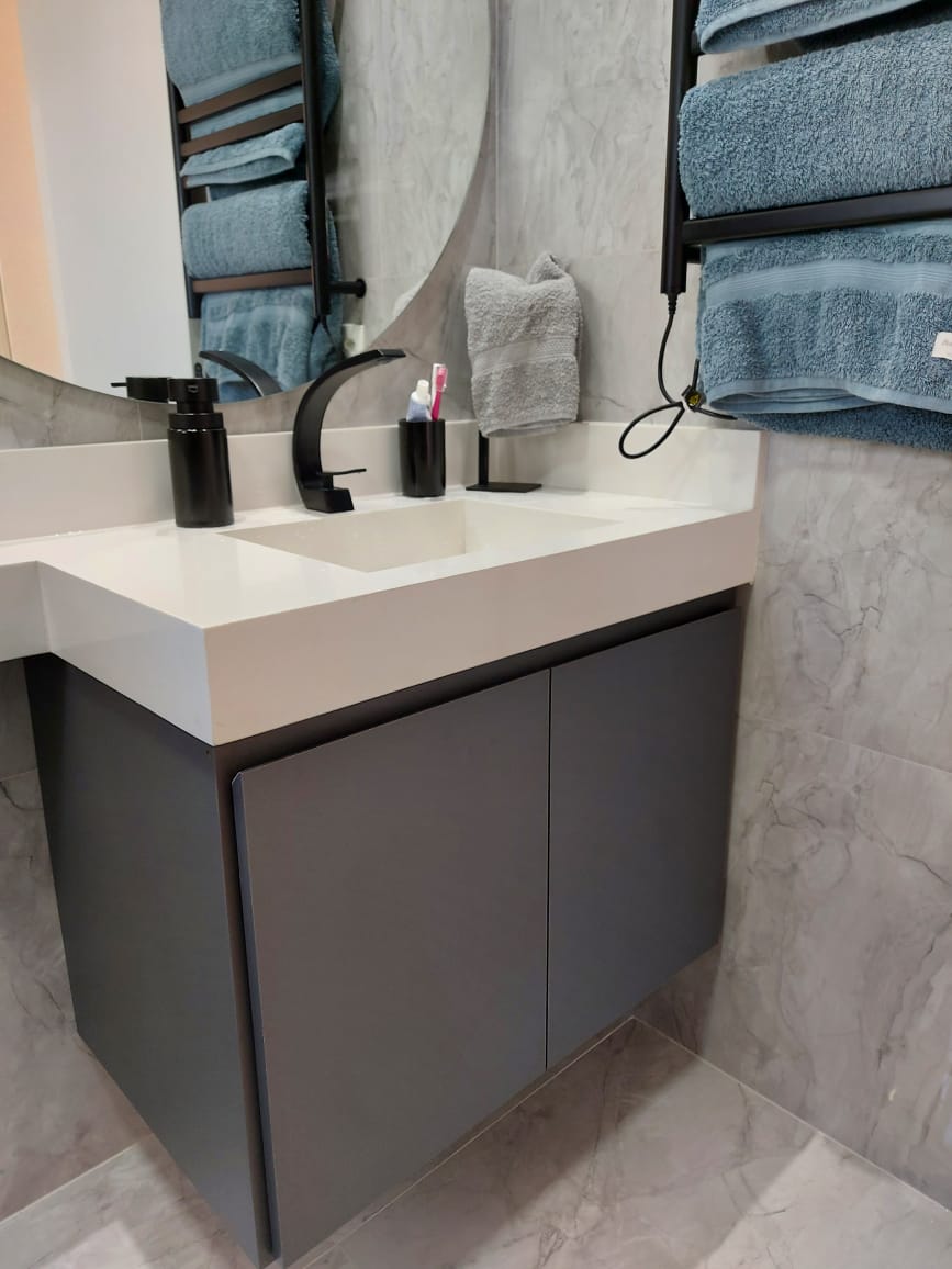 Um banheiro com pia, espelho e toalheiro.