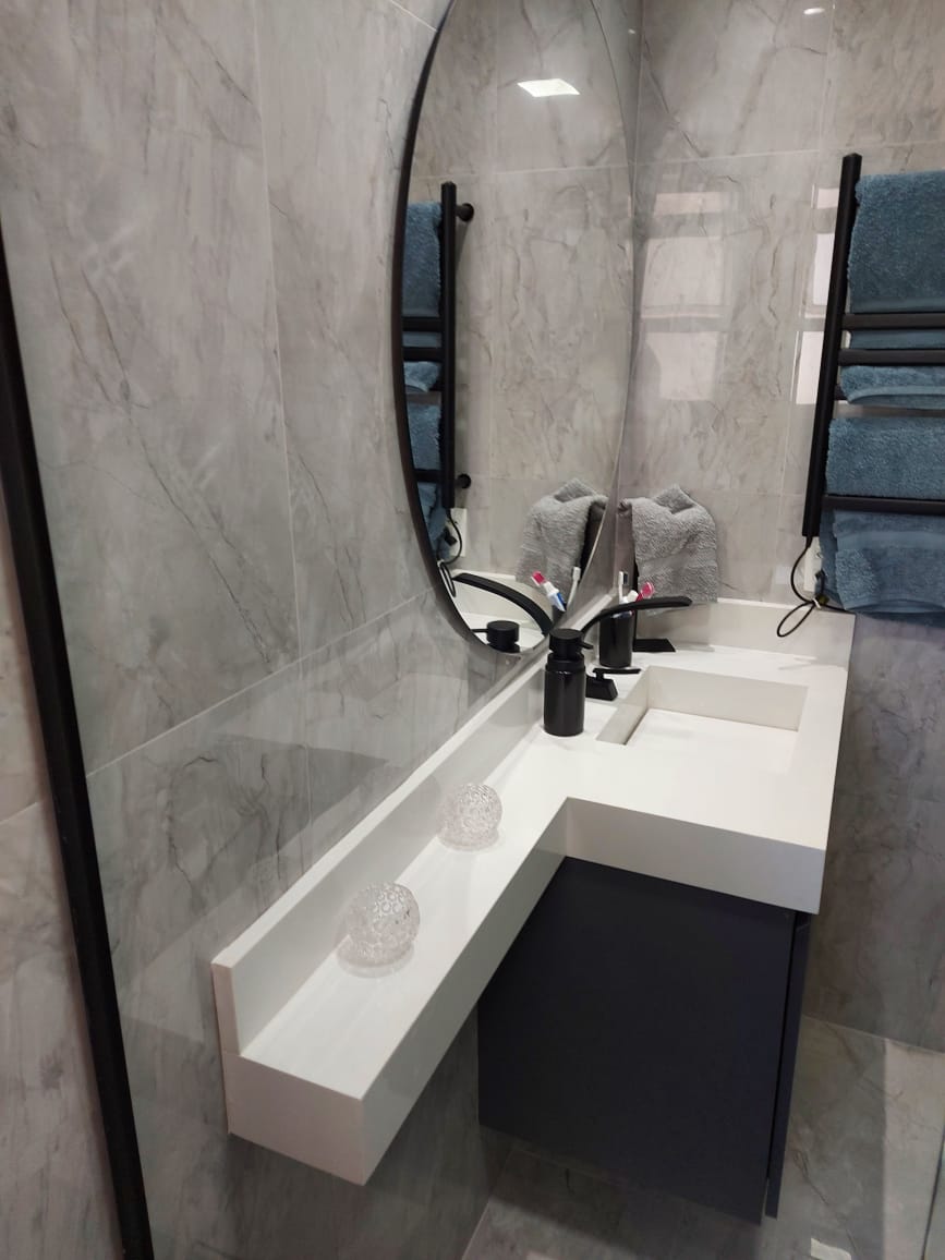 Um banheiro com duas pias e espelho redondo.