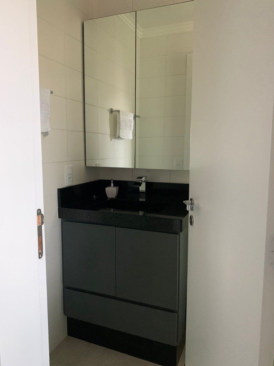 Um banheiro com pia e espelho acima.