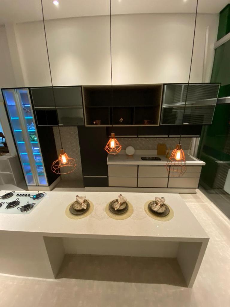 Uma cozinha com três pratos na bancada e três luminárias penduradas no teto.