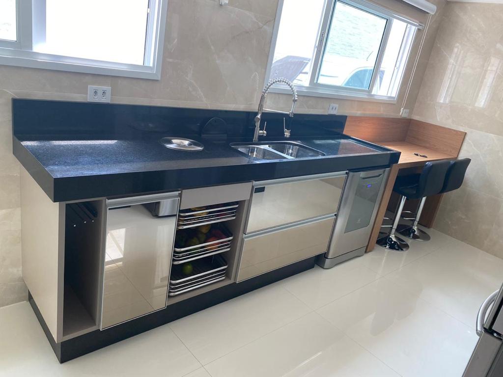 Uma cozinha com pia, lava-louças e bancos.