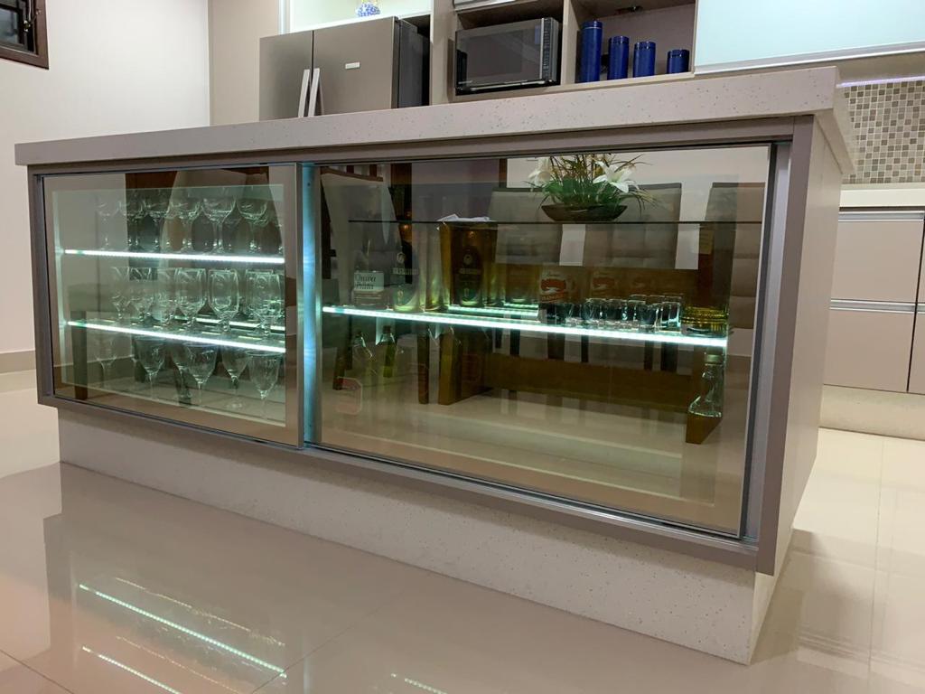 Uma ilha de cozinha com uma porta de vidro cheia de taças de vinho e garrafas.