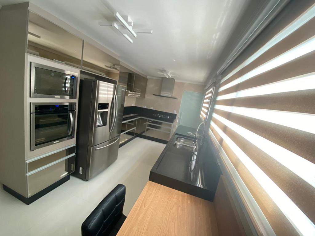 Uma cozinha com utensílios de aço inoxidável, geladeira, micro-ondas e pia.