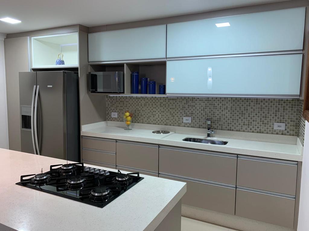 Uma cozinha com fogão, forno, geladeira, pia e micro-ondas.
