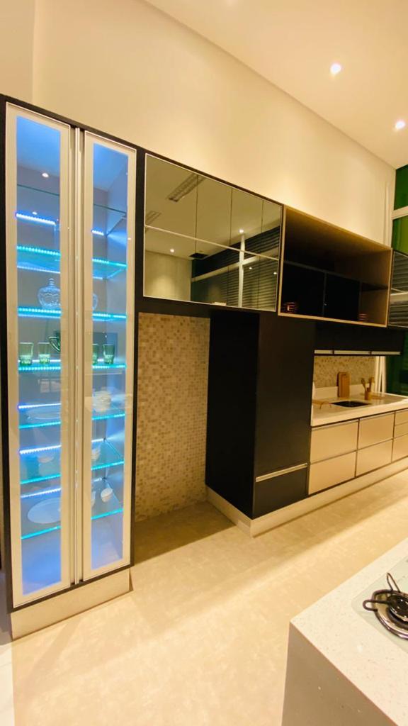 Uma cozinha com muitos armários e uma geladeira com porta de vidro.