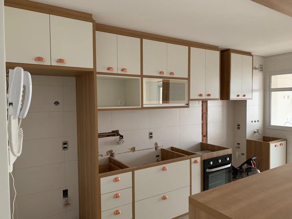 Uma cozinha com armários brancos e bancadas de madeira.