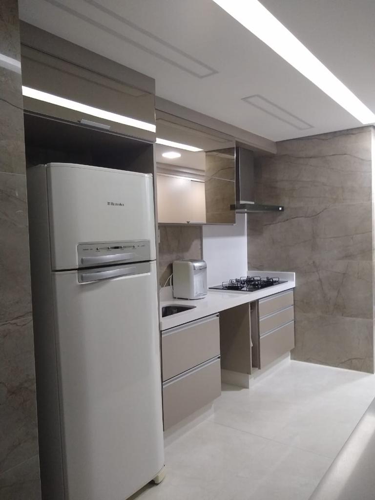 Uma cozinha com geladeira, fogão, pia e micro-ondas.