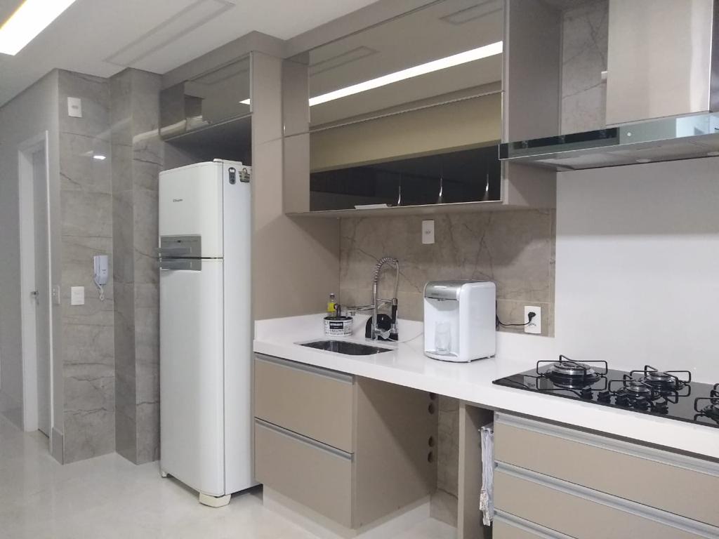 Uma cozinha com geladeira, fogão e pia