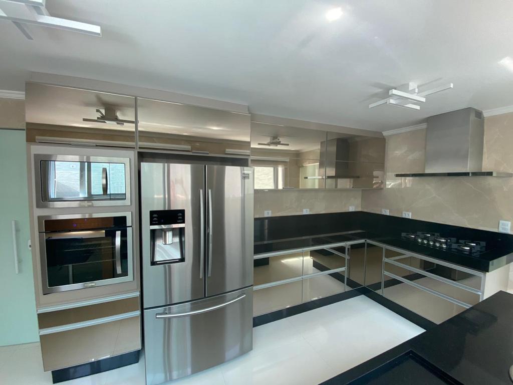 Uma cozinha com eletrodomésticos em inox e armários espelhados.