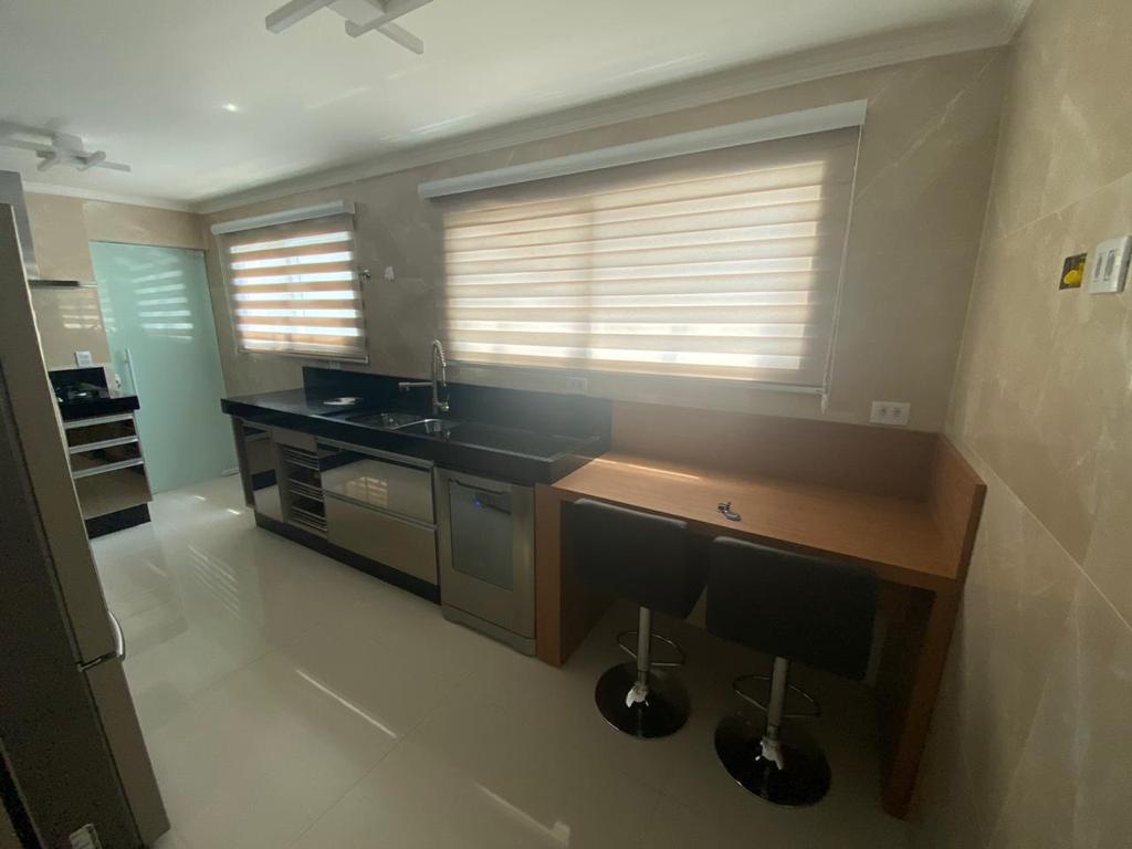 Uma cozinha com mesa, bancos e geladeira.