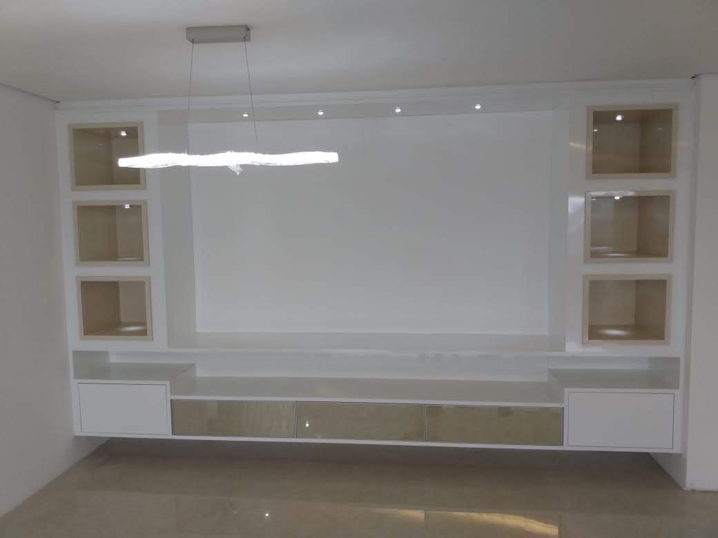 Uma sala de estar com um grande centro de entretenimento e uma luz pendurada no teto.