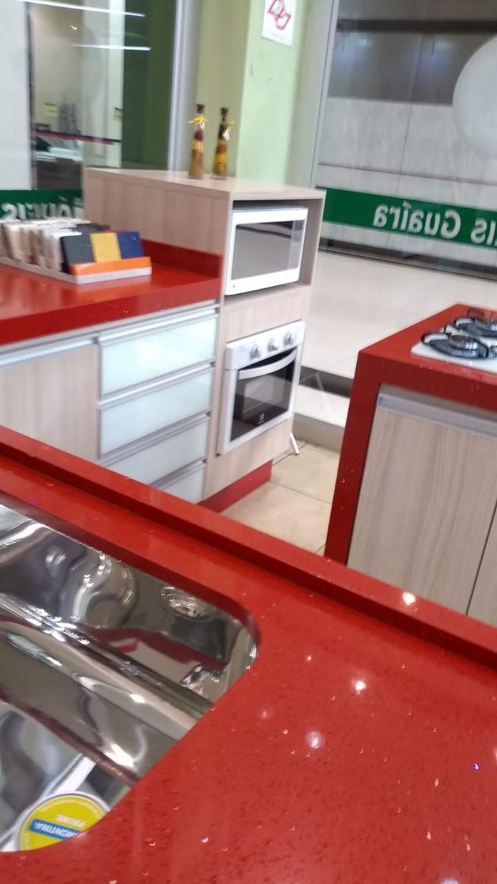 Uma cozinha com bancadas vermelhas e armários brancos