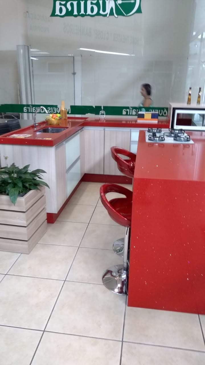 Uma cozinha com uma bancada vermelha e uma placa verde acima dela