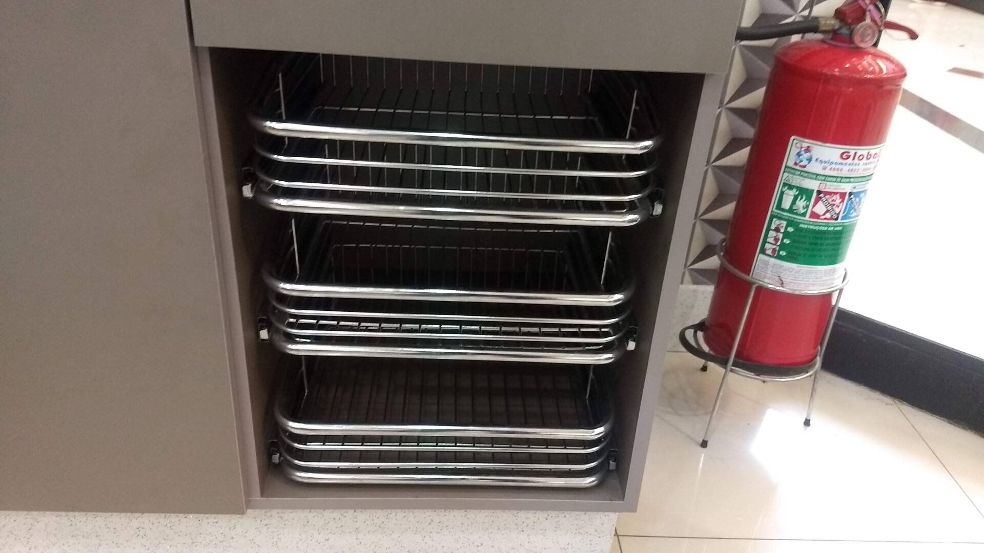 Um extintor de incêndio está ao lado de uma pilha de cestos de metal.