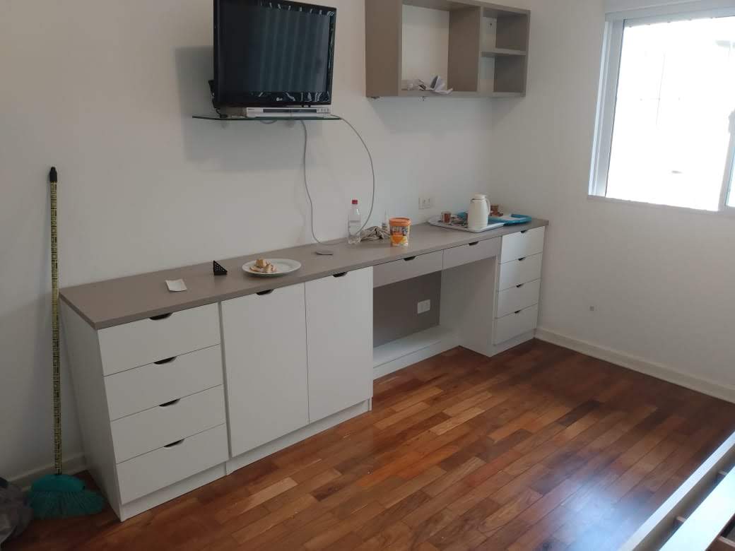 Uma sala com piso de madeira e uma televisão na parede.