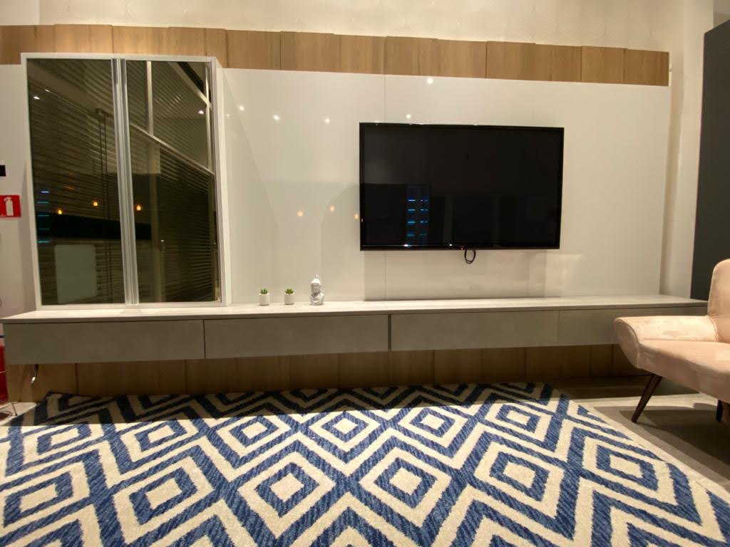 Uma sala com tapete e uma TV de tela plana na parede.